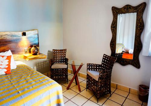 a bedroom with a bed and a mirror and a chair at Casa del Sol Inn in Ajijic