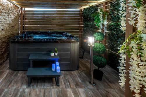 ein Badezimmer mit einer Badewanne, einer Bank und Pflanzen in der Unterkunft Suite SPAtio - Jacuzzi Privé - 20min Disneyland PARIS in Pézarches