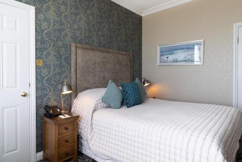 a bedroom with a bed and a nightstand with a bed sidx sidx sidx sidx at Langham Hotel Eastbourne in Eastbourne