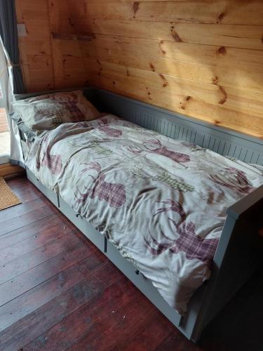a bed in a room with a wooden wall at Pod 4 in Skail