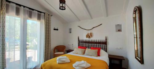 a bedroom with a bed with red pillows and a window at Finca La Meica B&B in Casabermeja