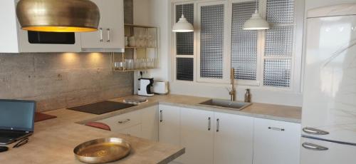 a kitchen with white cabinets and a laptop on a counter at Primera Línea Pau 5 - Playa de San Juan in Playa de San Juan