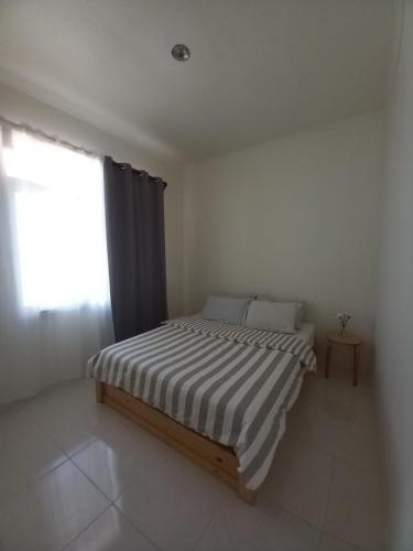 uma cama num quarto branco com uma janela em Shambala palm beach anyer em Anyer