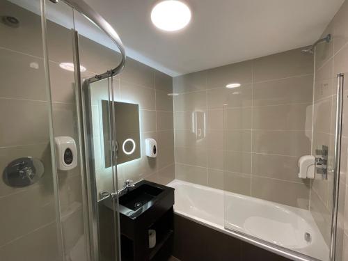 Old Mill Hotel & Lodge في باث: حمام مع دش وحوض استحمام ومغسلة