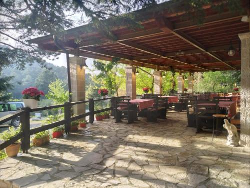 un patio con pergolato in legno, tavoli e sedie. di Guesthouse Alberti Llogara a Shalë