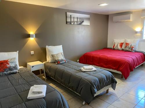 um quarto com 2 camas e um cobertor vermelho em LOGIS Hôtel La Chaumière em Marseillan