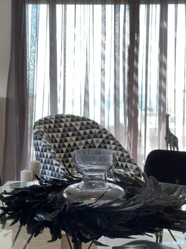 a glass vase on a table in front of a chair at Athenean Modern Escape near Marina Flisvos in Athens