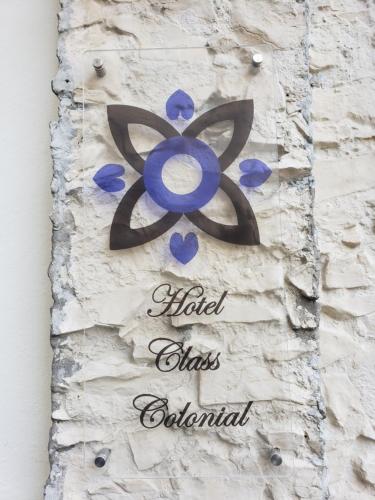 a sign on a brick wall with a blue flower at Hotel Class Colonial in Santo Domingo