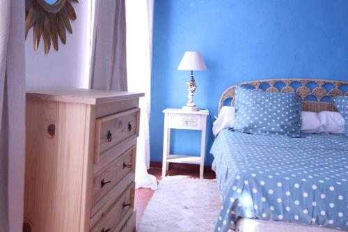 ein blaues Schlafzimmer mit einem Bett, einer Kommode und einer Lampe in der Unterkunft Studio la maison bleue in Cotignac