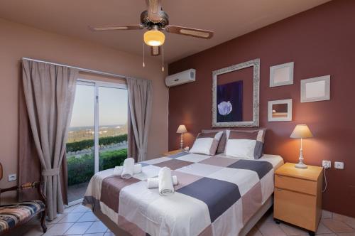 a bedroom with a large bed with a large window at Villa René in Koskinou