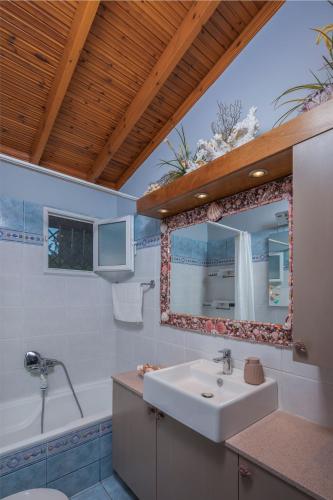 a bathroom with a sink and a tub and a mirror at Villa René in Koskinou