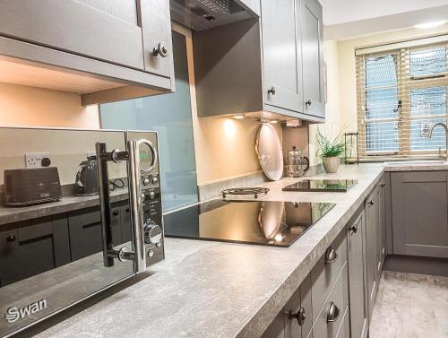 a kitchen with stainless steel appliances and gray cabinets at The Terrace at Riverside Suites in Bridgnorth