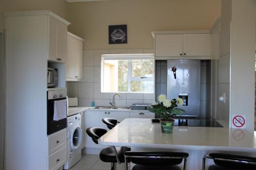 a kitchen with white cabinets and a table with flowers on it at W8 - Goose Valley Golf Estate in Plettenberg Bay