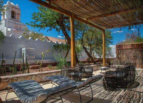 un patio con sillas, mesas y una pérgola en Terrantai Lodge, en San Pedro de Atacama