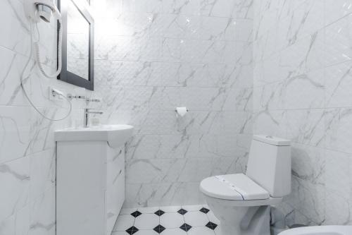 a white bathroom with a toilet and a sink at Opera Passage Hotel & Apartments in Lviv