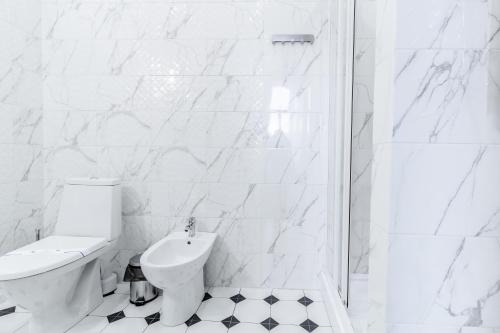 a white bathroom with a toilet and a shower at Opera Passage Hotel & Apartments in Lviv