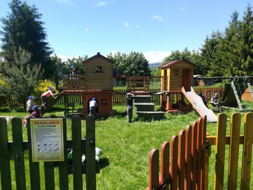 un parque infantil con una valla de madera en el césped en Stanica pod Zadzierną Kemping Domki letniskowe, en Lubawka