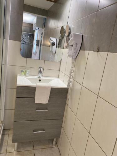 a bathroom with a sink and a mirror at LOGIS Hôtel La Chaumière in Marseillan