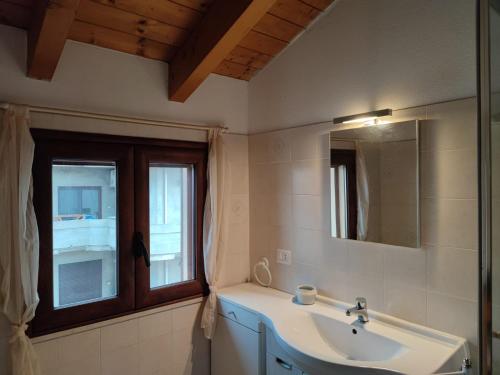 a bathroom with a sink and a mirror and a window at Cagliari Elmas Airport Beautiful Mansarda in Assemini