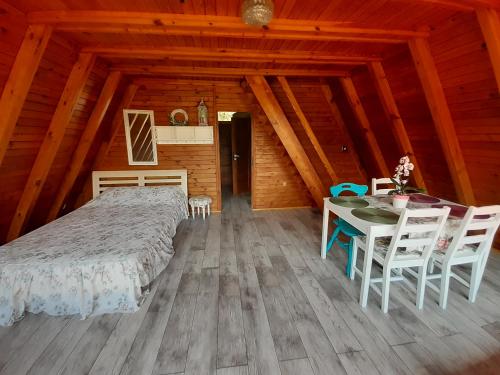 a bedroom with a bed and a table and chairs at Domki pod Dębami in Trzcianka