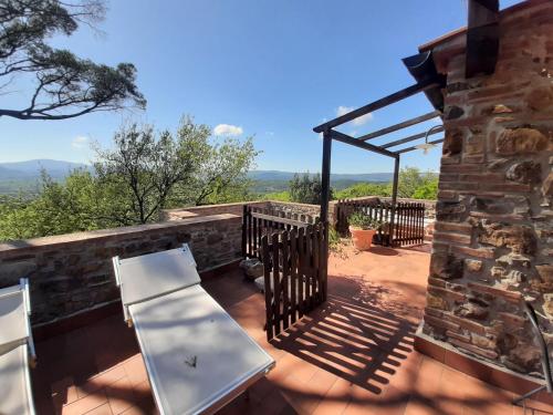 a patio with a bench and a stone wall at Agriturismo e Glamping Serraiola Alta in Frassine