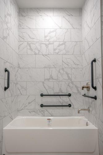 a white bath tub in a bathroom with marble walls at The Schoolhouse Hotel, Trademark Collection by Wyndham in White Sulphur Springs