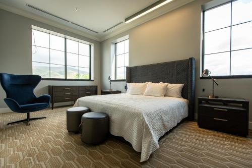 a bedroom with a bed and a chair and windows at The Schoolhouse Hotel, Trademark Collection by Wyndham in White Sulphur Springs