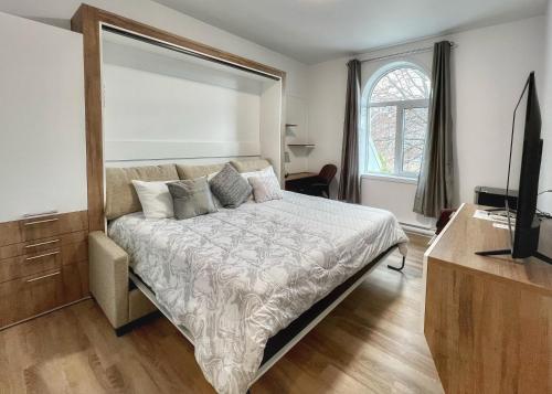 Un dormitorio con una cama con una cómoda y un televisor. en Auberge Le St-Alexis, en La Baie