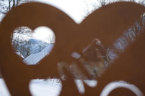 a view of a house through a heart shaped window at Ferienwohnung Stoablick - barrierefrei mit Bergblick in Bad Goisern