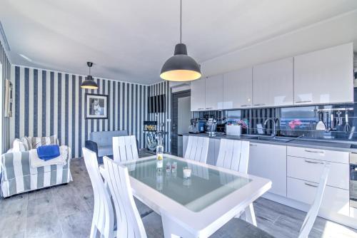 a kitchen with a glass table and white chairs at Villa Belissima Vista Mare in Selce