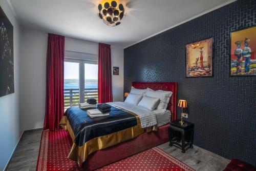 a bedroom with a bed with red curtains and a window at Villa Belissima Vista Mare in Selce