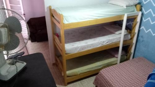 a small room with a bunk bed with a fan at Mongaguá House in Mongaguá