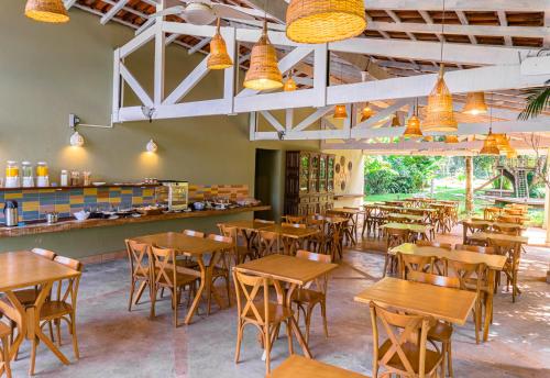 um restaurante vazio com mesas e cadeiras de madeira em Pousada Vila Jacaa em Ubatuba