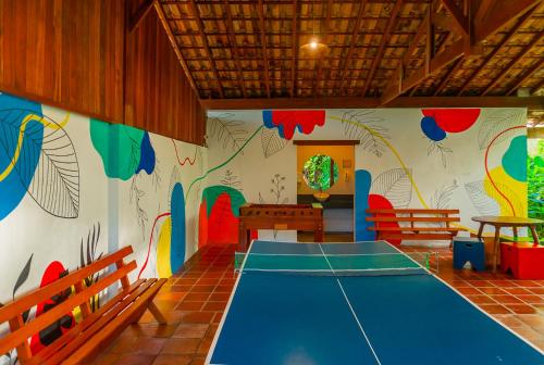 um quarto com uma mesa de pingue-pongue e um mural na parede em Pousada Vila Jacaa em Ubatuba