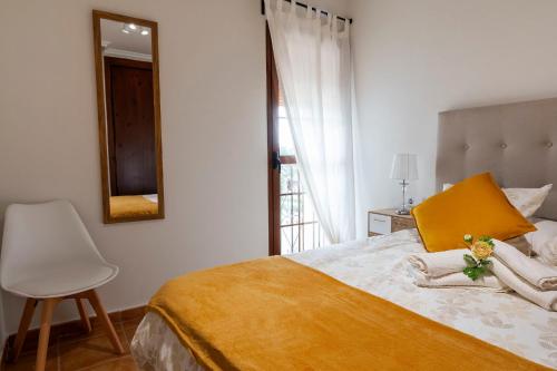ein Schlafzimmer mit einem Bett, einem Spiegel und einem Stuhl in der Unterkunft Ático con terraza-solárium y piscina 4-6 personas WIFI A/C in Roda