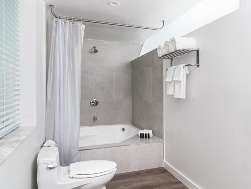 a white bathroom with a toilet and a bath tub at Essex House Hotel in Miami Beach