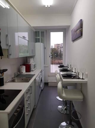 a kitchen with a sink and a counter with chairs at Minimalist Apartment Located near Belém in Lisbon