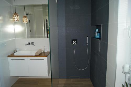 La salle de bains est pourvue d'un lavabo et d'une douche avec un lavabo. dans l'établissement Apartament, à Ostróda