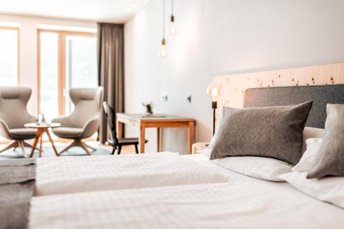 a bedroom with a bed and two chairs and a desk at Seehotel Panorama Relax in Resia