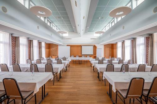 a large room with tables and chairs in it at Szent János Hotel in Mohács