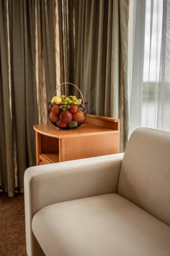 a bowl of fruit on a table next to a couch at Szent János Hotel in Mohács