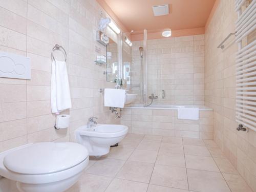 a white bathroom with a toilet and a sink at Szent János Hotel in Mohács