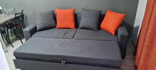 a couch with orange and gray pillows on it at Apartment near the Beach Batumi-Gonio in Gonio