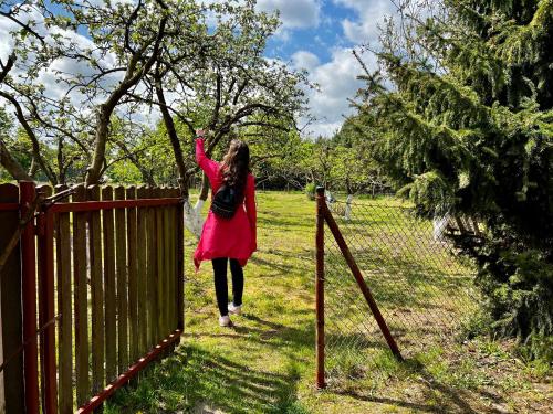 a woman in a red dress is standing next to a fence at Domek nad Wartą in Międzychód