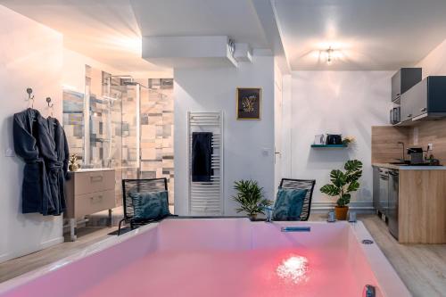 un salon avec une table rose et une cuisine dans l'établissement Suite SPAradise - SPA Privé - 6min Disneyland PARIS, à Chalifert
