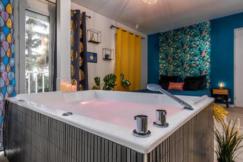 a large bath tub in a room with blue walls at Suite SPAradise - SPA Privé - 6min Disneyland PARIS in Chalifert