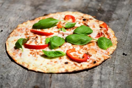 a pizza with tomatoes and basil on a wooden table at wecamp Reserva Alecrim in Santiago do Cacém