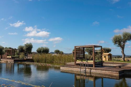 a park with a playground next to a body of water at wecamp Reserva Alecrim in Santiago do Cacém
