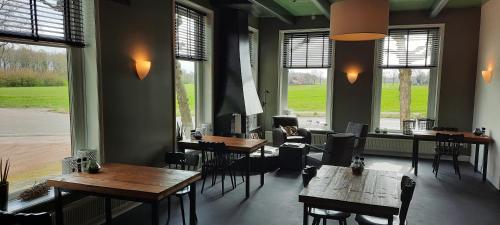 a restaurant with wooden tables and chairs and windows at Herberg Boswijck, B&B in Wijckel