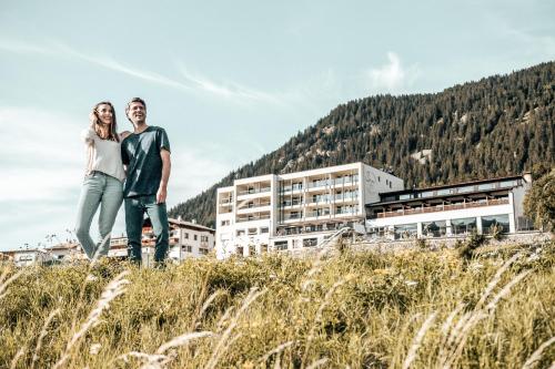 a couple standing on a hill in front of a building at Seehotel Panorama Relax in Resia